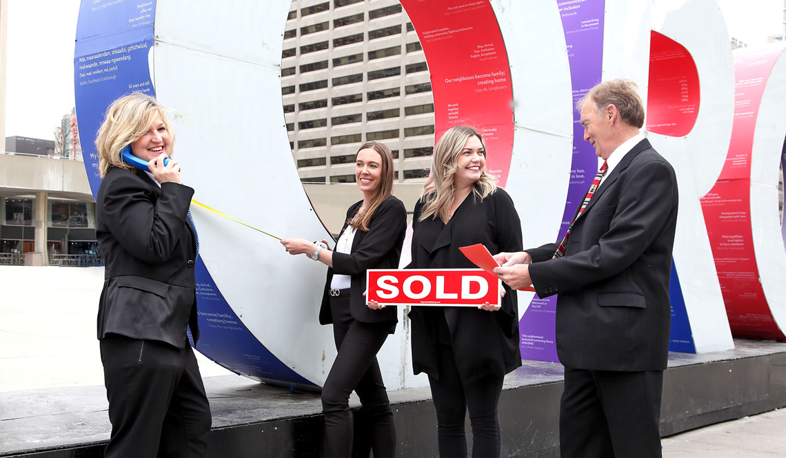 Real estate team celebrating with sold sign